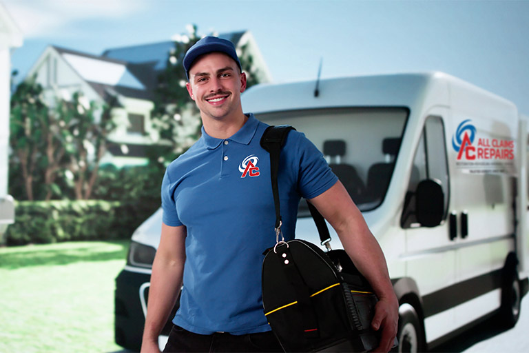 all-claims-worker A man in a blue shirt and jeans stands beside a parked van, smiling at the camera.